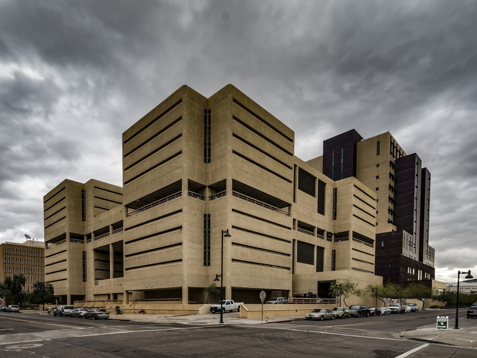 beige brutalist concrete asymmetrical building against a cloudy sky