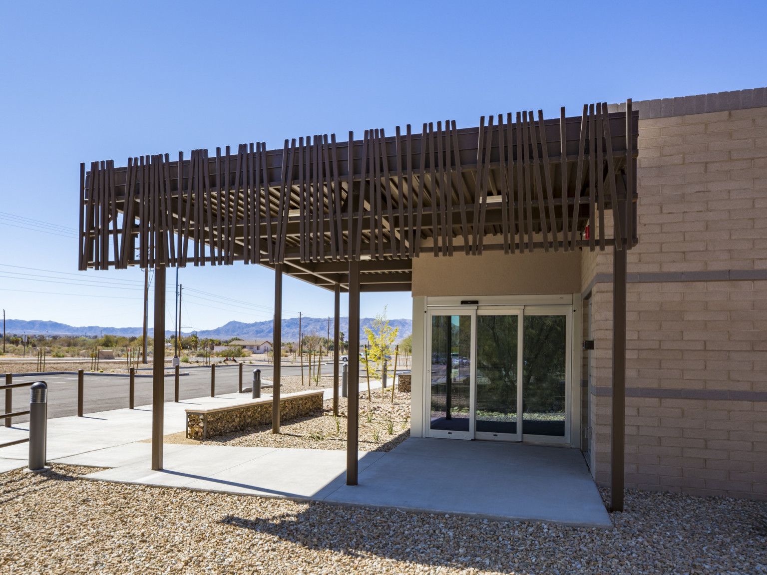 Front entry of brick building with sliding glass door under brown overhang with abstract shading design on the side