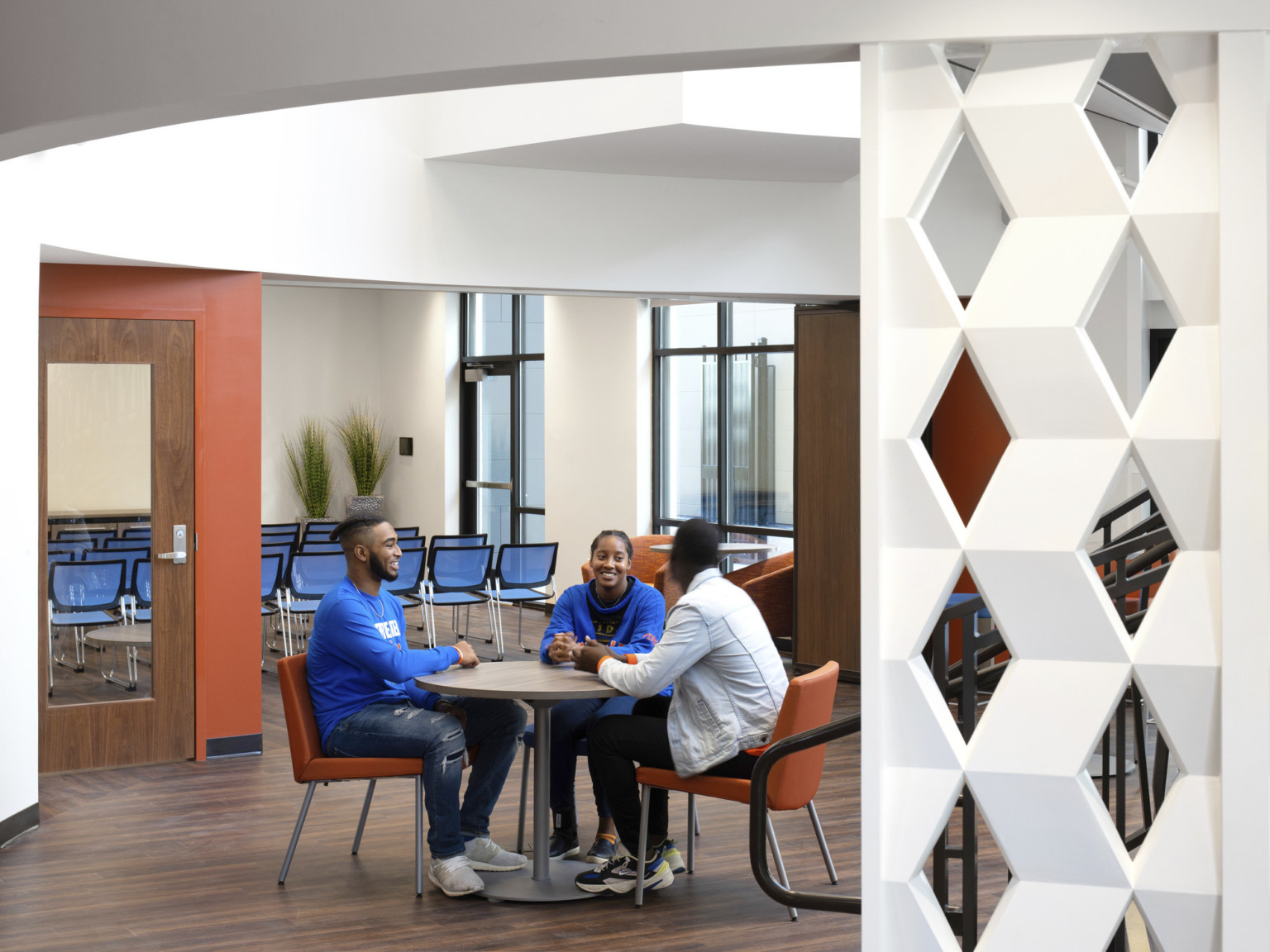 Seating area in lobby framed by white geometric panel of woven zigzags