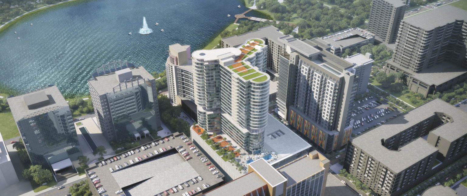 Aerial view of back of building with roof top gardens and pool in city near water