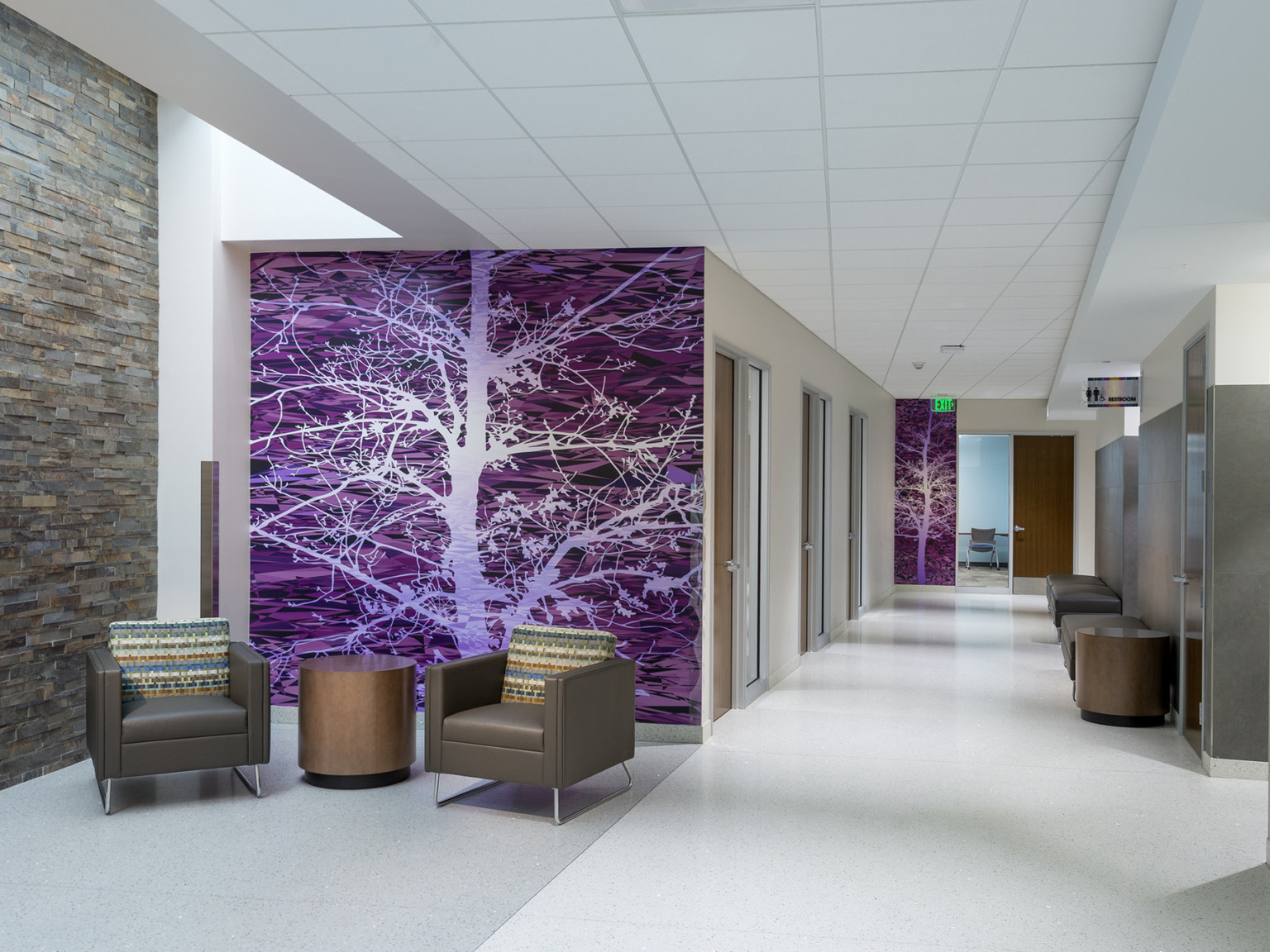 Seating area in front of purple abstract mural at end of hallway