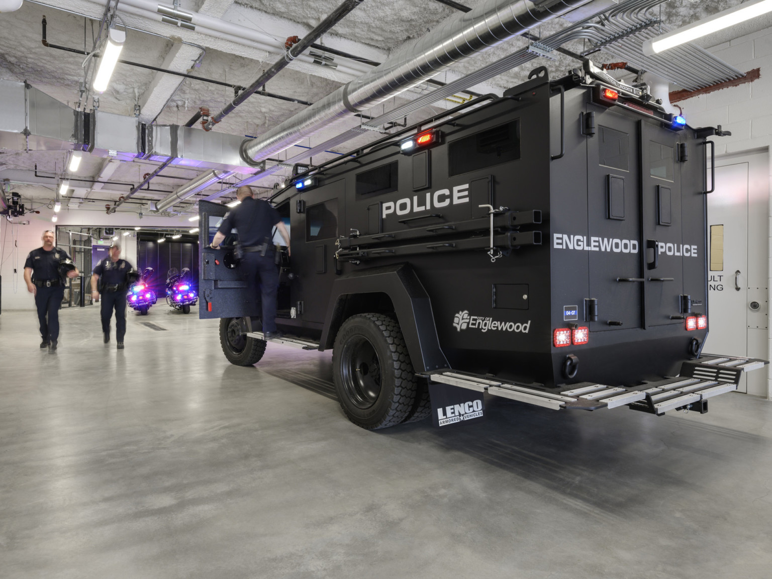 Englewood Police armored truck in garage with exposed ductwork and white pipes at textured white ceiling