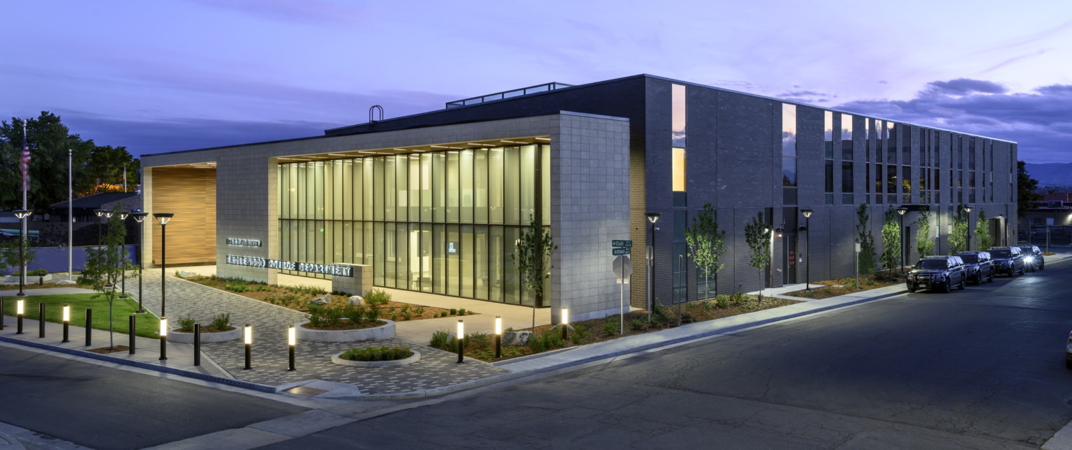 Corner view of building showing full length of structure with entry illuminated in the evening