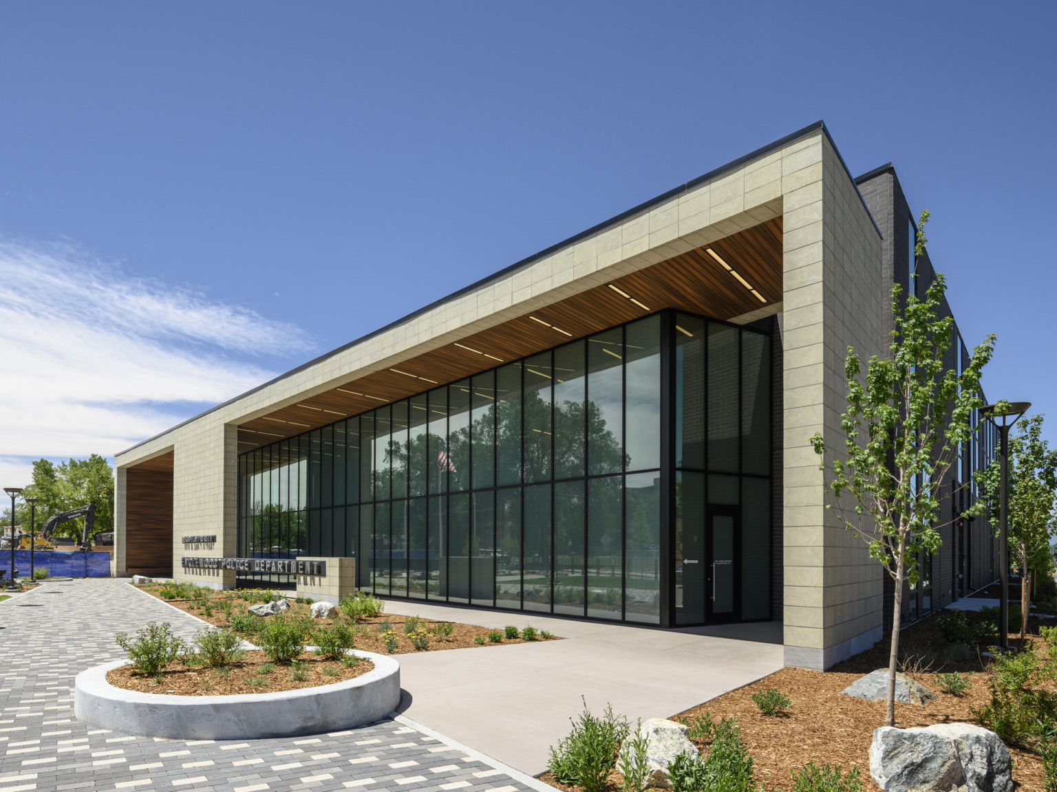 Corner view of building entry with signage center, stone overhang design envelopes double height windows