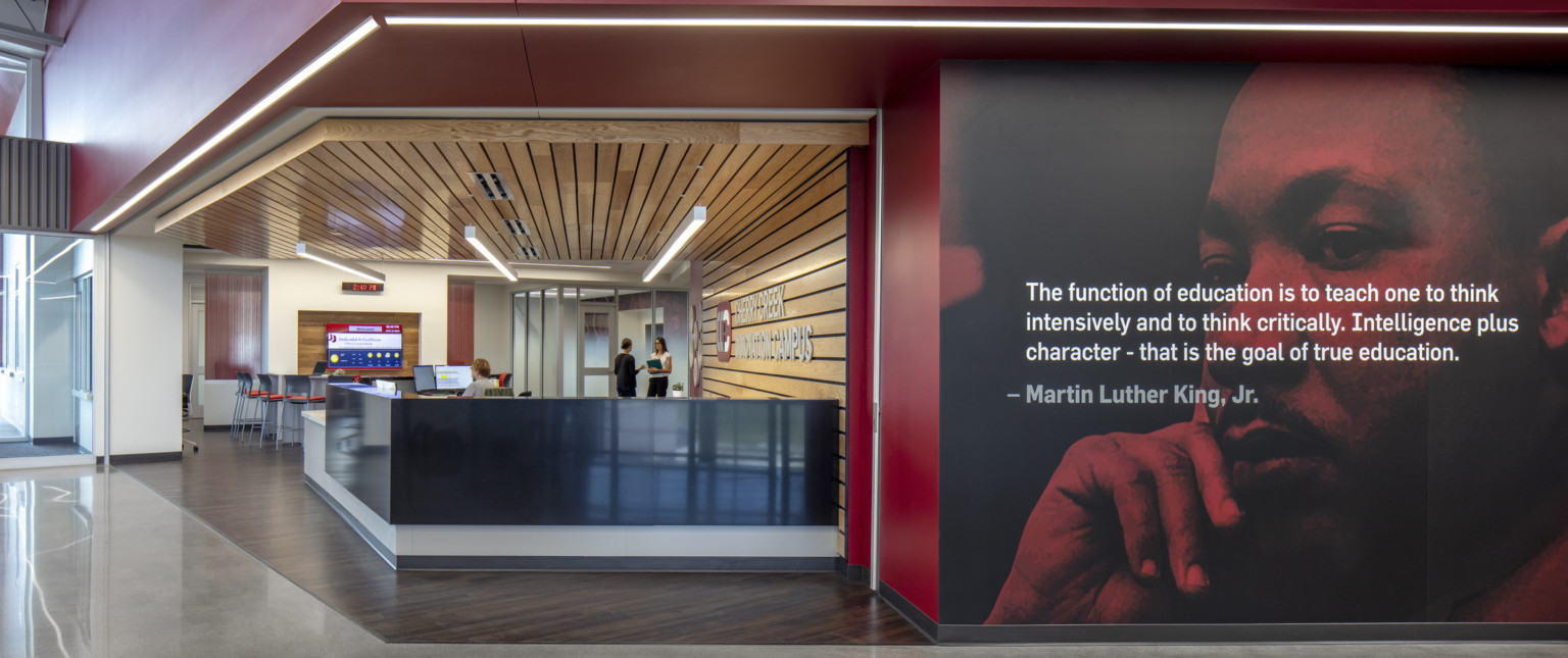 Black reception desk in wood panel recessed room off hallway with photo mural of Martin Luther King Jr. with quote overlaid
