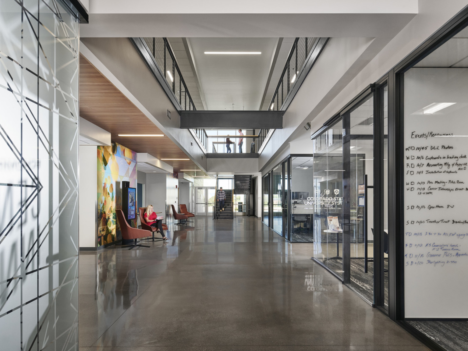 Private work areas with glass walls in space below upper walkway. Translucent wall and door with geometric design, right