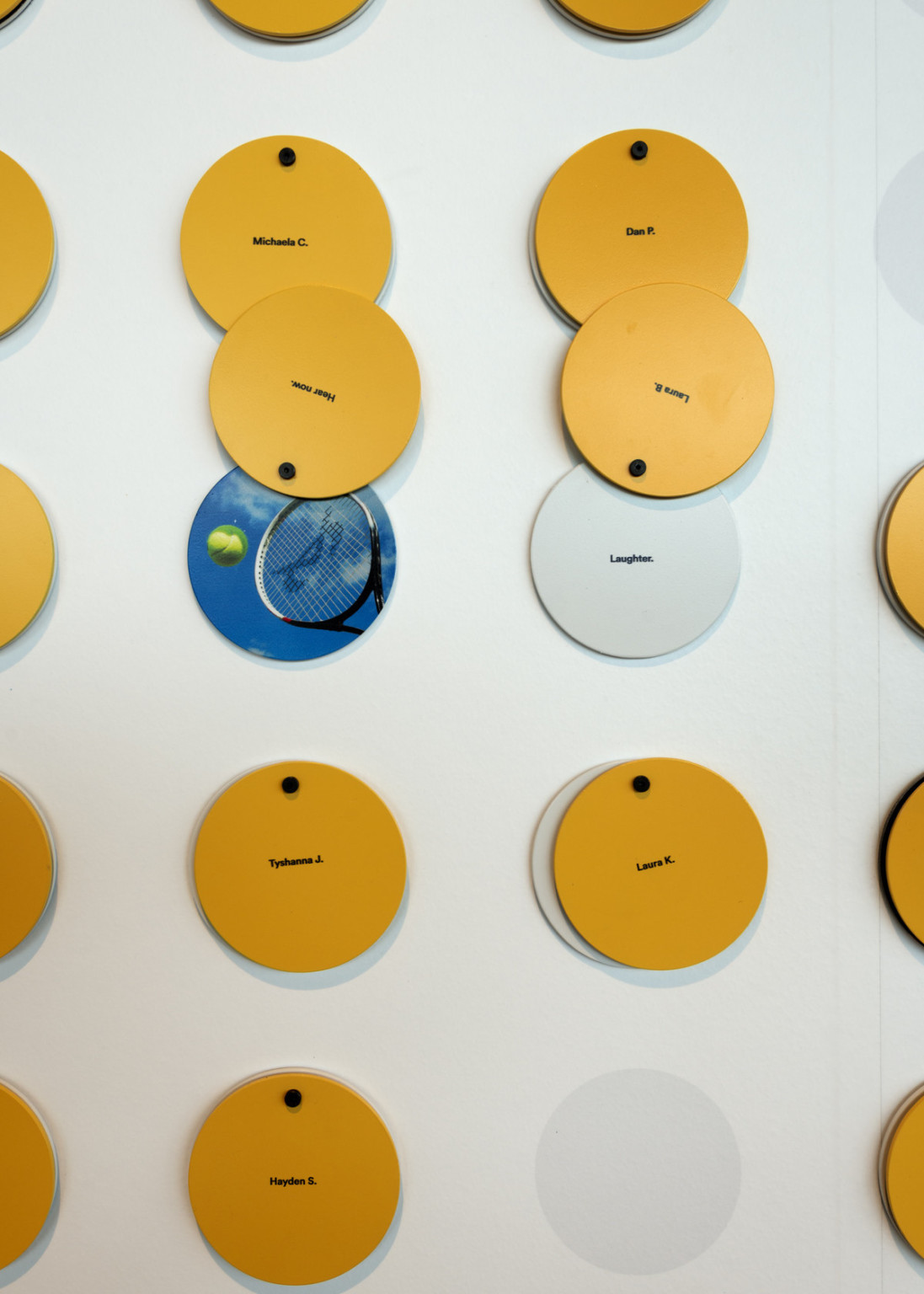 Layered circles hang on white wall with yellow top layer, words and images