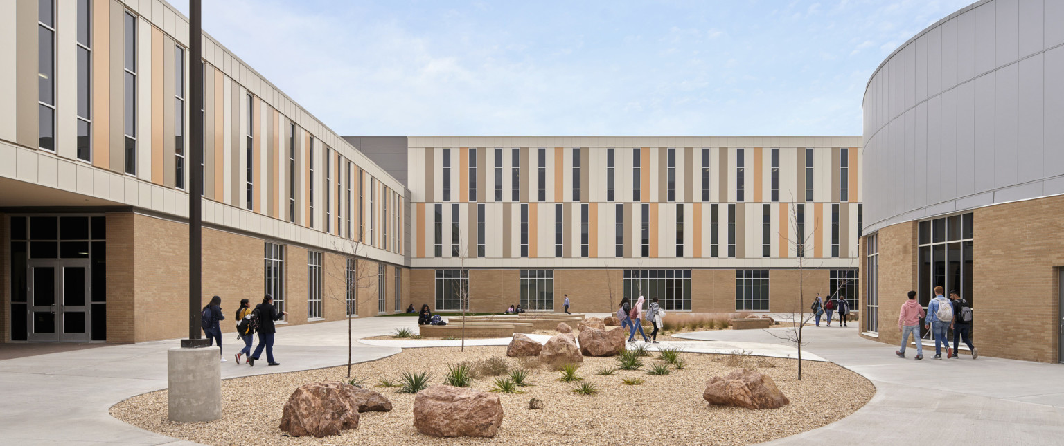 Courtyard with rock garden and organic stone benches. L shaped building at front and left, with rounded addition to the right