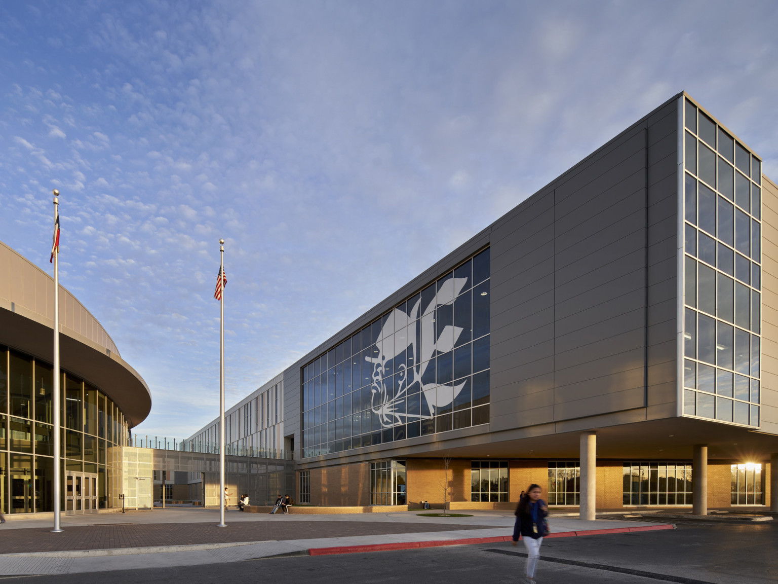 Exterior corner view of same building. Elevated extensions covers walkway below and ends in a wall of windows