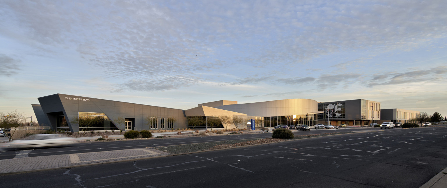 Exterior view from parking lot of angled black and white sections of building extending from rounded central structure