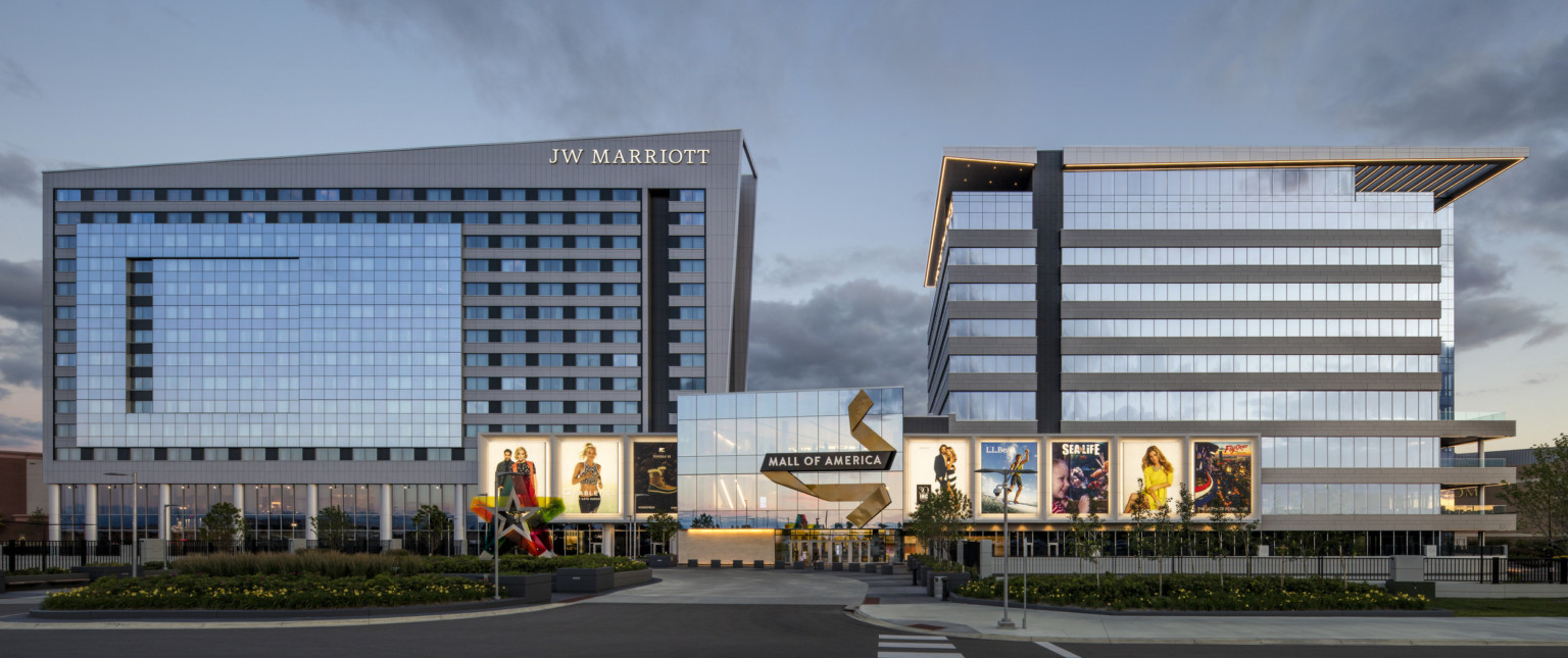 Mall of America entry with illuminated signage connects 2 grey angled buildings. Left building has JW Marriott written at top