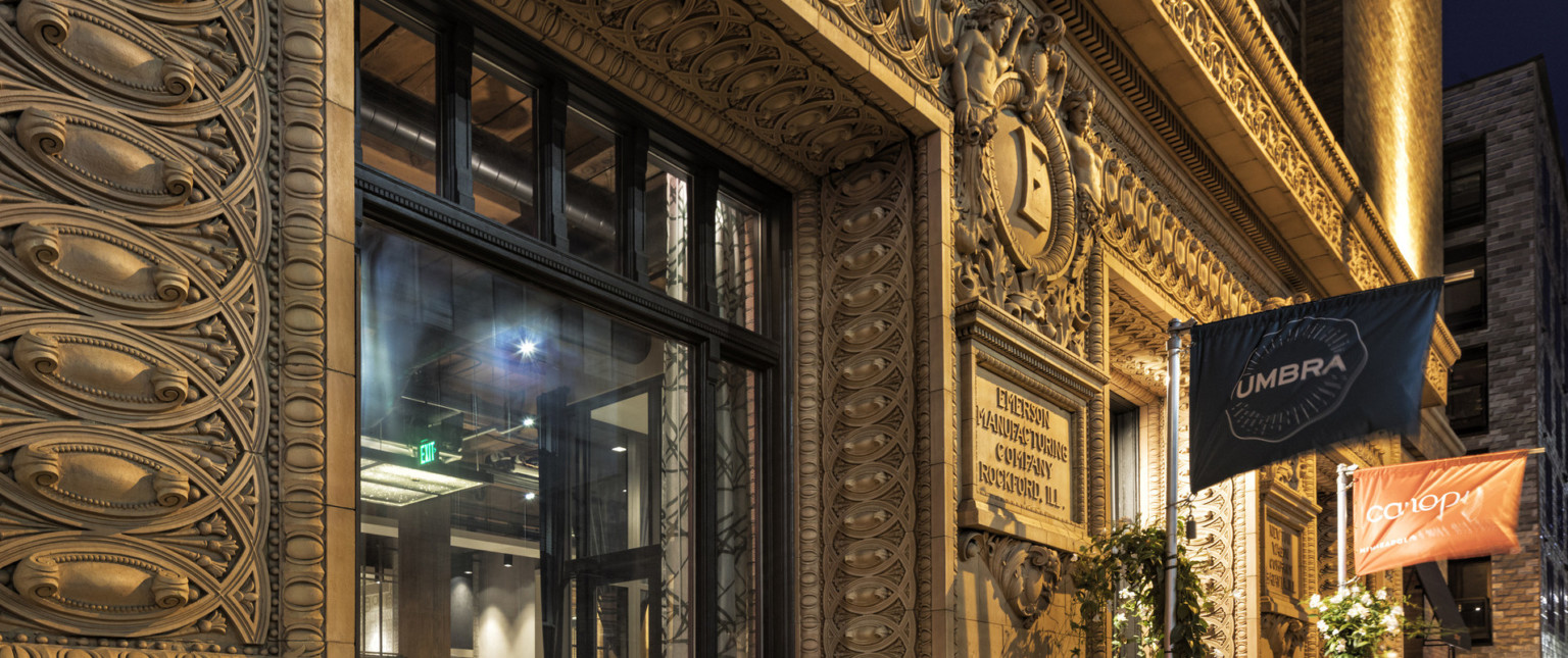 Ornate carved stone molding around entry with historic carved sign reading Emerson Manufacturing Company Rockford, Ill., adaptive reuse hotel