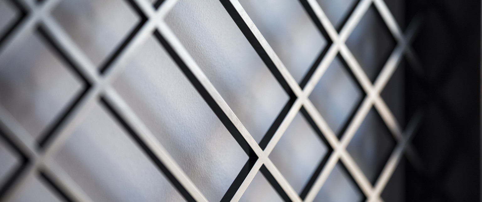 Closeup of dark metallic grid against grey background