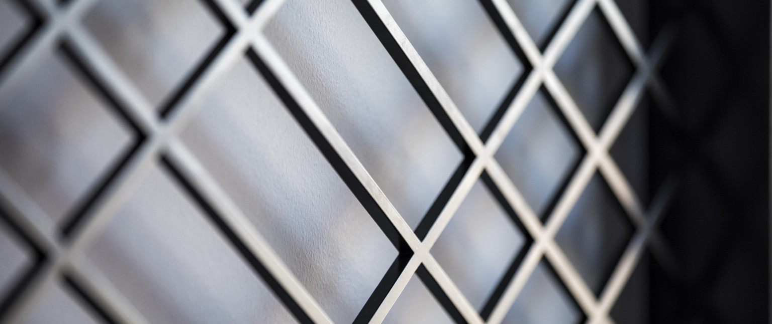 Closeup of dark metallic grid against grey background, adaptive reuse hotel