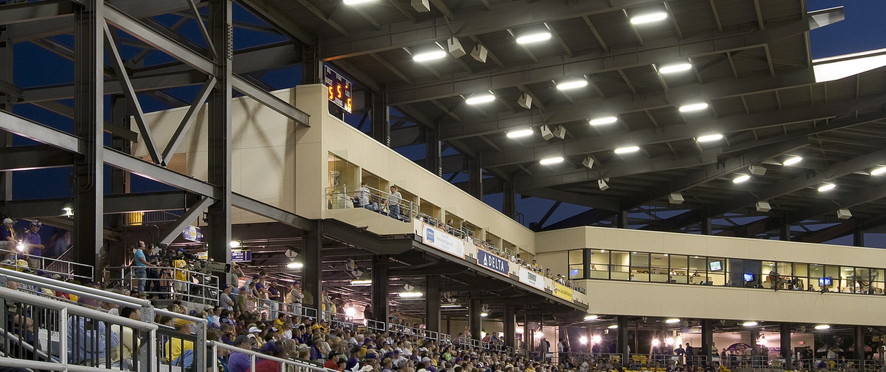 View from lower deck looking up to corner of cream colored box suites along first baseline with press box behind home plate