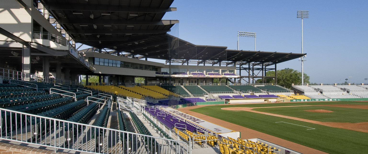 Black awning extends from boxes sheltering seats and supports net behind home plate. 1st baseline dugout labeled LSU Baseball