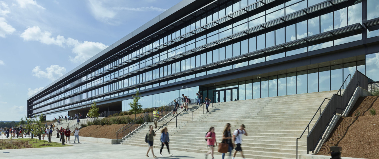 2 sets of wide concrete steps in front of floor to ceiling windows and glass entry doors. Steps separated by hill with trees