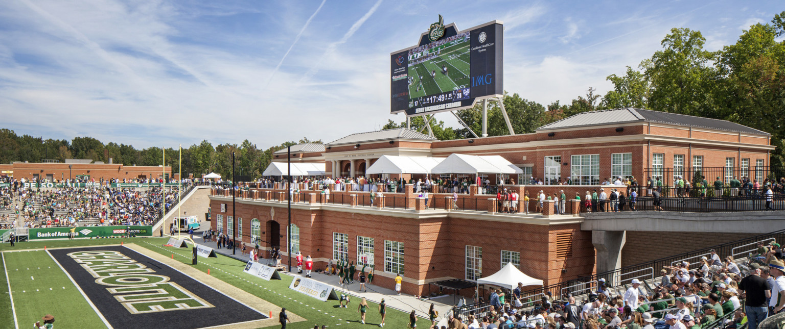 View from stands looking to brick building at end zone. 2nd floor walkway leads to patio with event space and end zone view