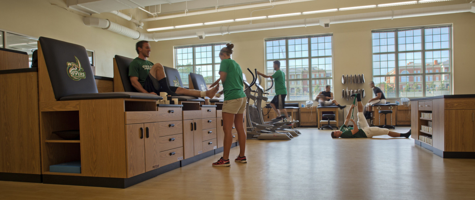 Elevated seats with wood cabinets underneath in window lined room with cardio equipment and space to stretch