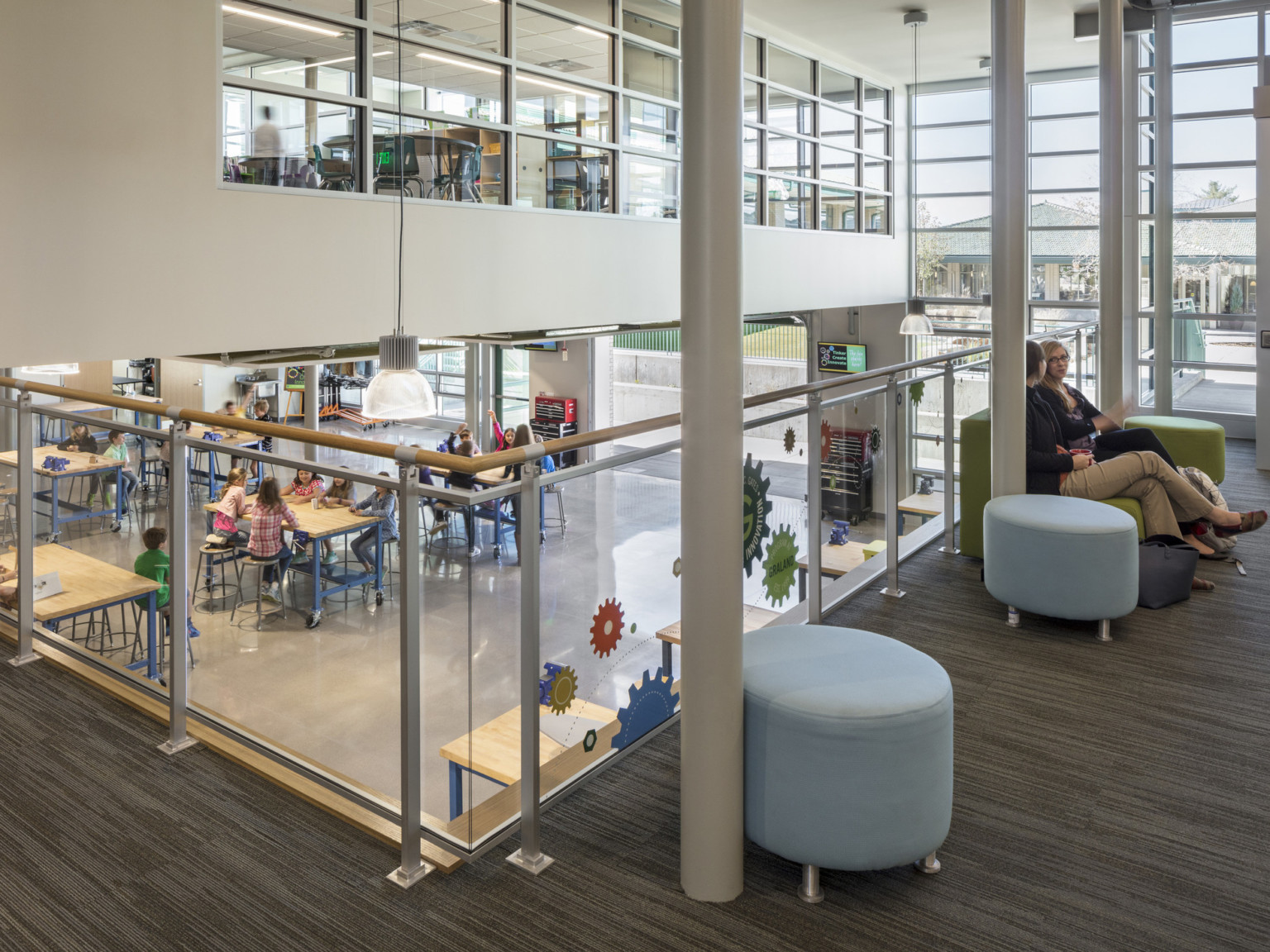 glass rail carpeted mezzanine overlooking open seating area next to exterior glass wall and cantilevered volume with windows