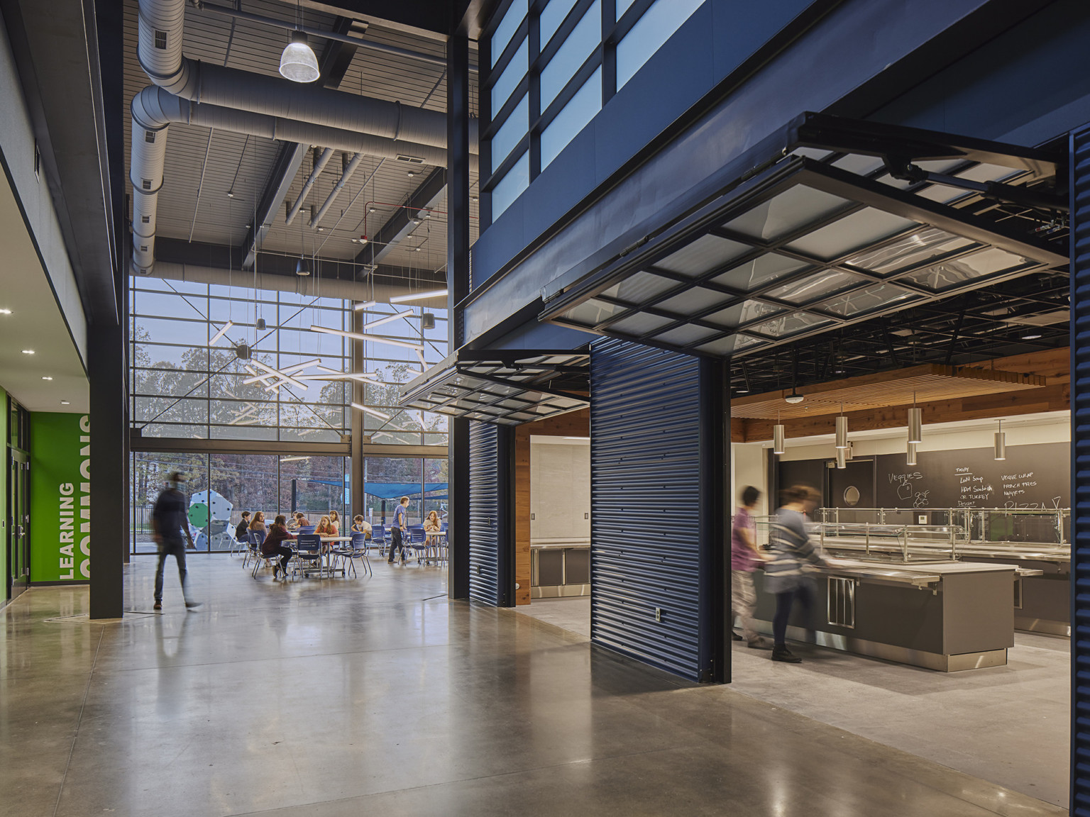 off a main hallway are blue colored garage doors that open to food and beverage area at high school