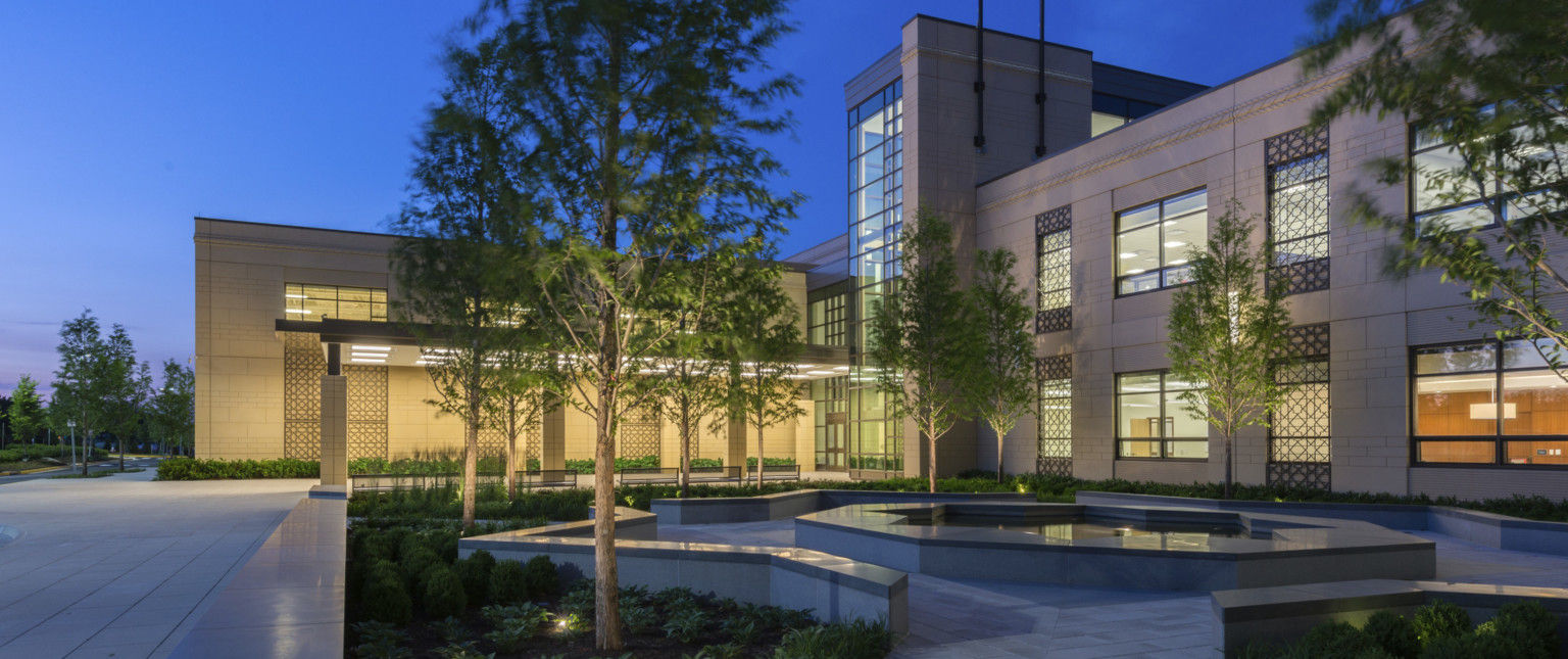 nighttime view of a school built with precast concrete façade, an illuminated canopy entrance leads to a double-height glass atrium