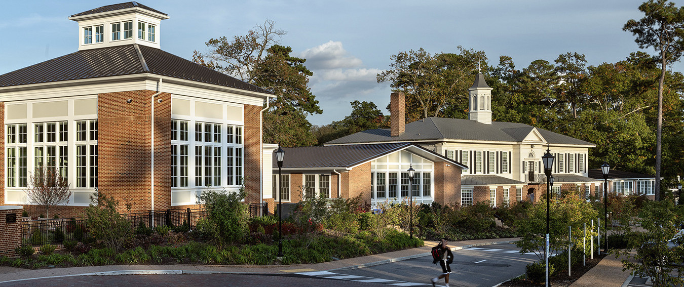 federal style brick buildings with black metal roof white trim and windows with white mullions along tree lined brick path