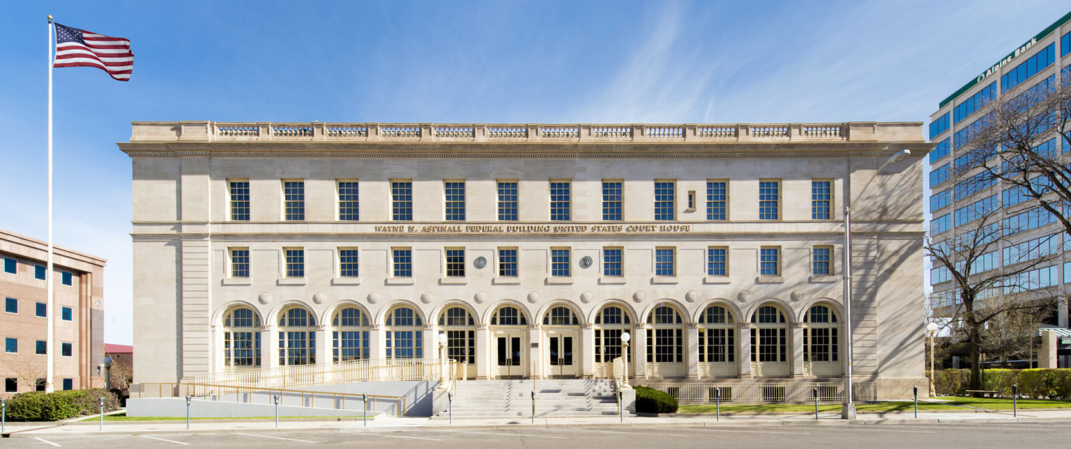 Front entry of a three story limestone Italian Renaissance Revival style building with ramp and gold toned railing at left
