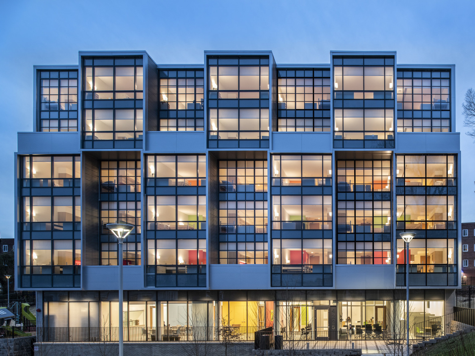 Exterior view of a section the Triumph with window covered facade illuminated at night with interior rooms visible