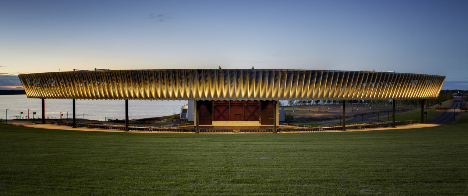 Paneled fascia partially illuminated from bottom over an amphitheater next to a body of water