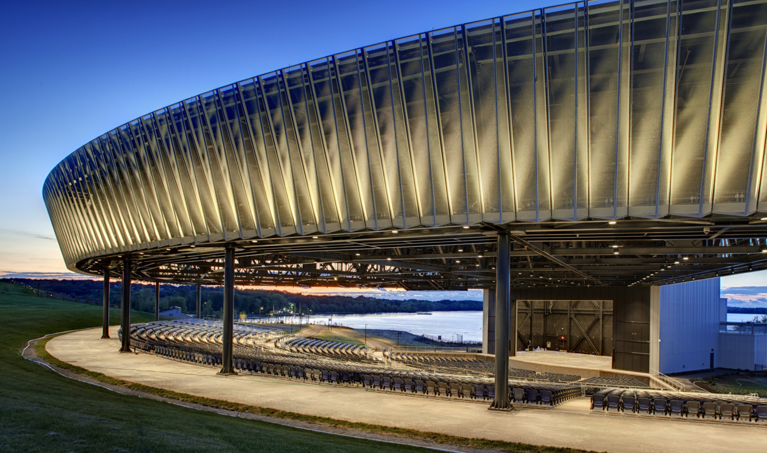 Evening view of perforated and sculpted outdoor amphitheater canopy at Onondaga Lakeview Amphitheater