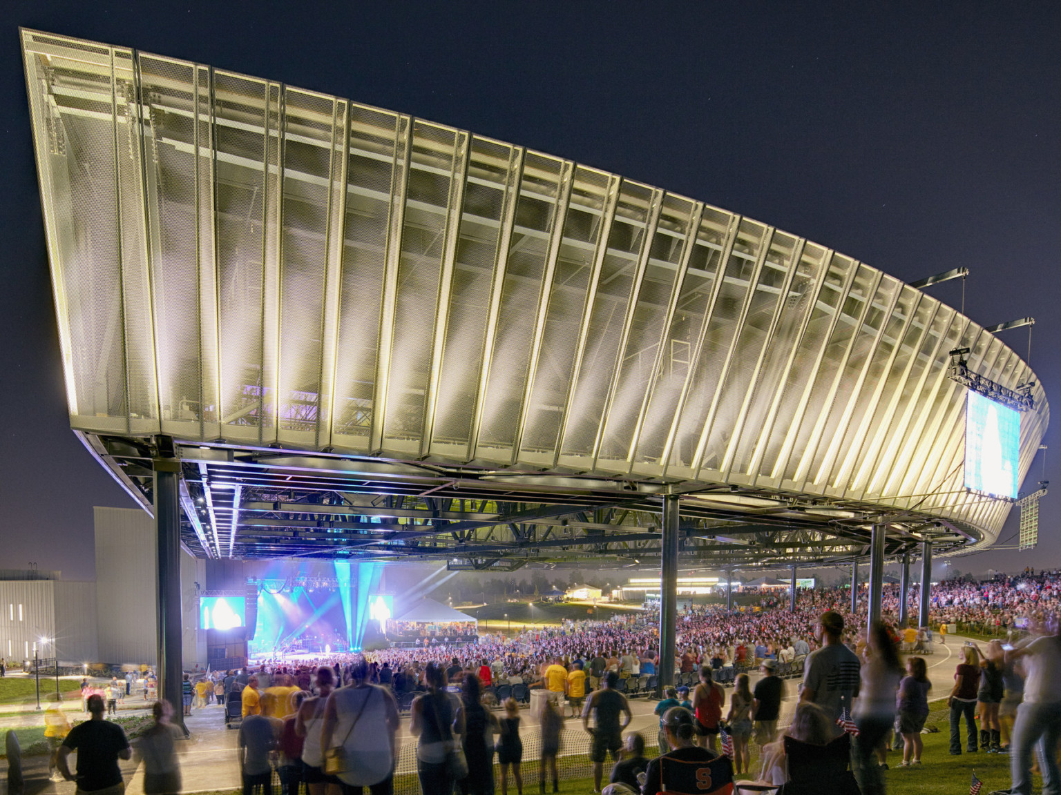 Amphitheater roof illuminated from lights on rafters viewed from front corner facing stage, showing ridges along fascia front