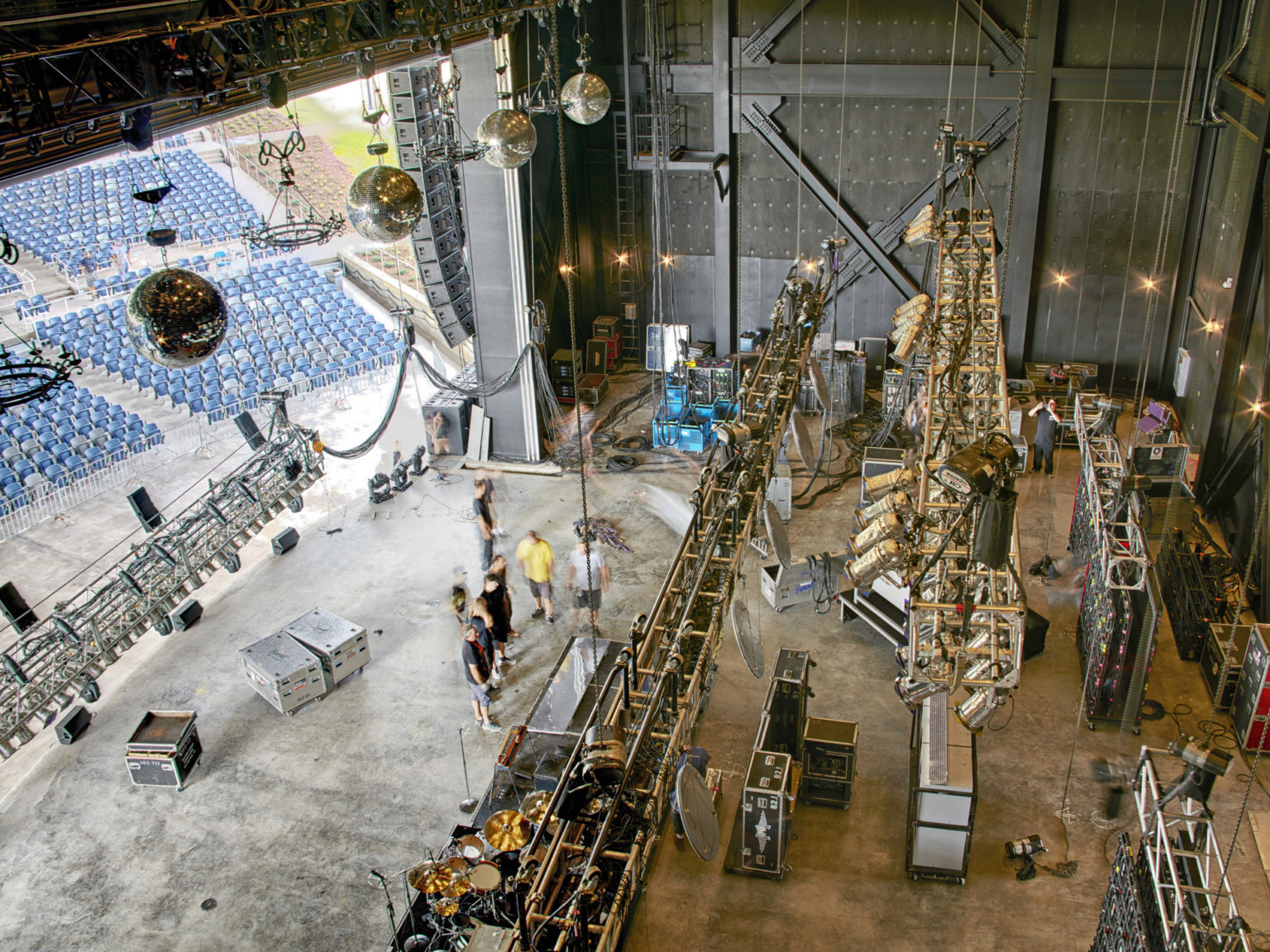 Backstage from above with multiple lighting systems lowered and sound equipment on stage