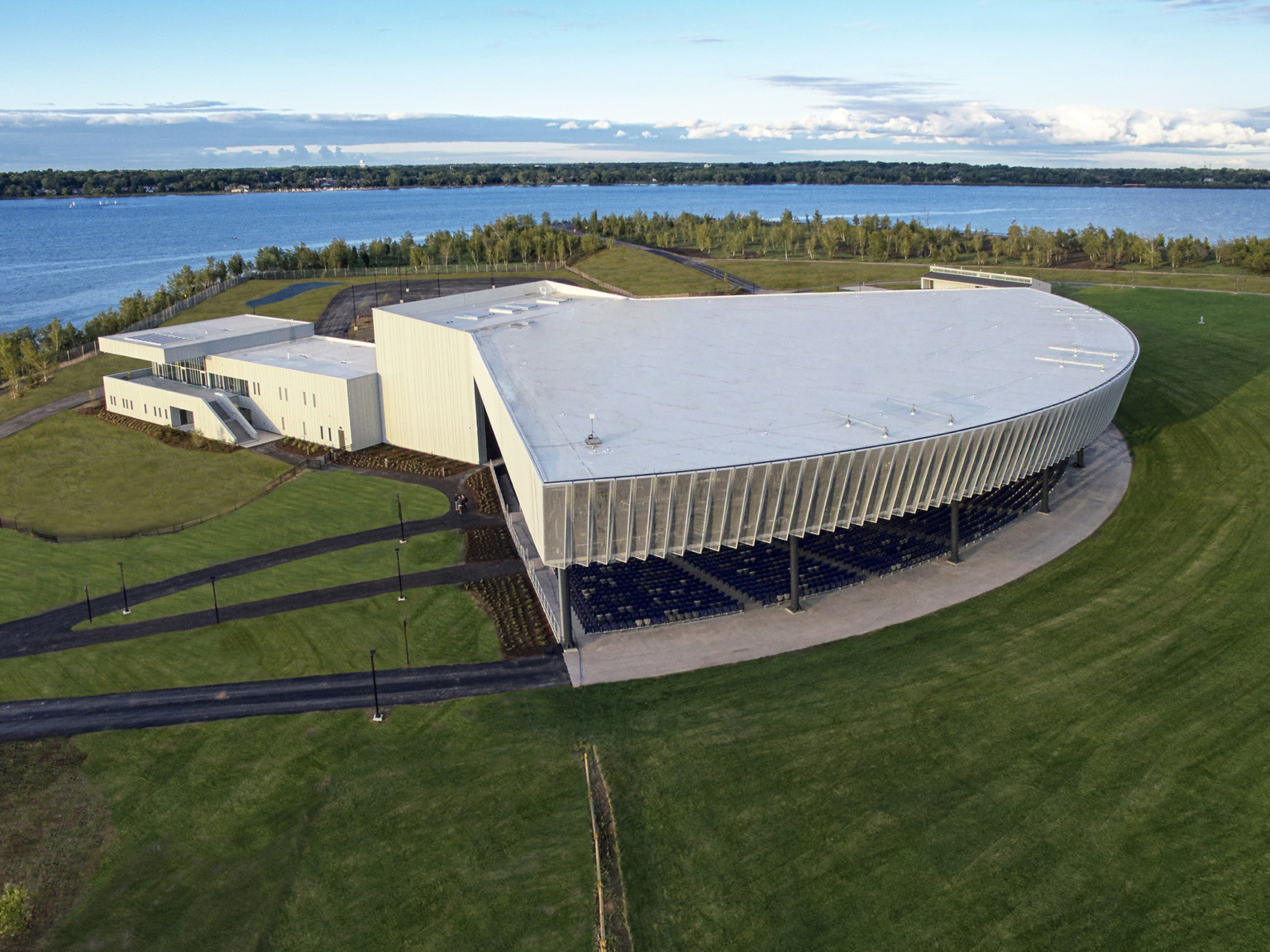 Amphitheater from above in a large green field with white building connected behind