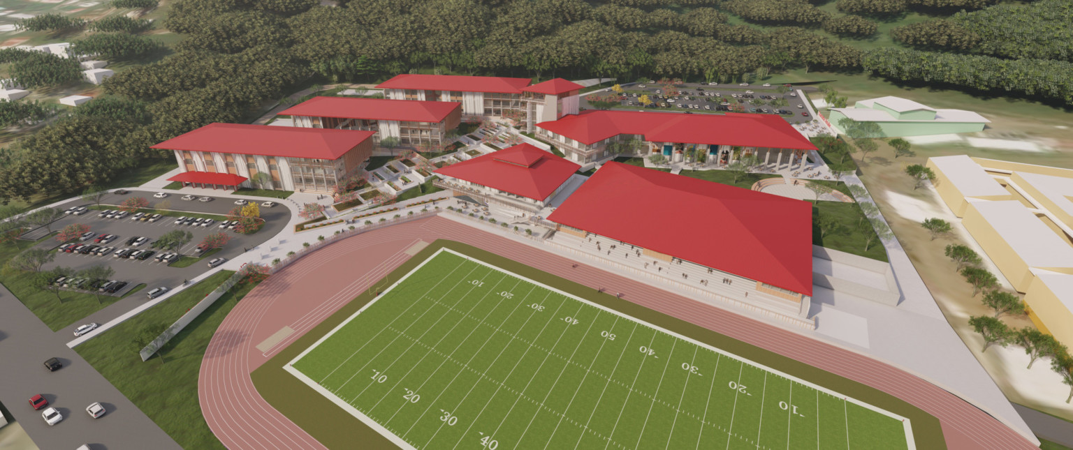 Aerial view of campus. 5 white multistory buildings with red roofs surround walkway and green space. Football field, front