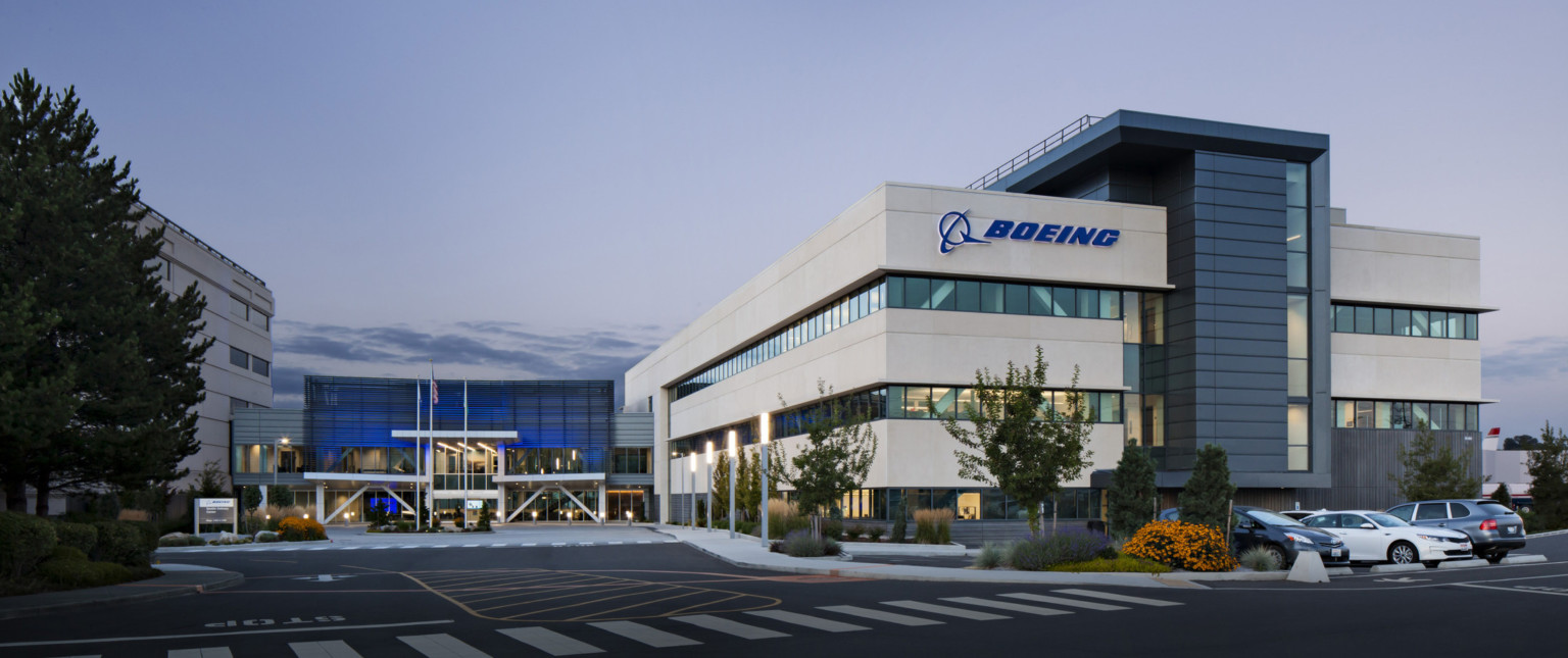 Boeing Seattle Delivery Center front entrance with logo on front of white wrapped facade. Blue recessed glass entry