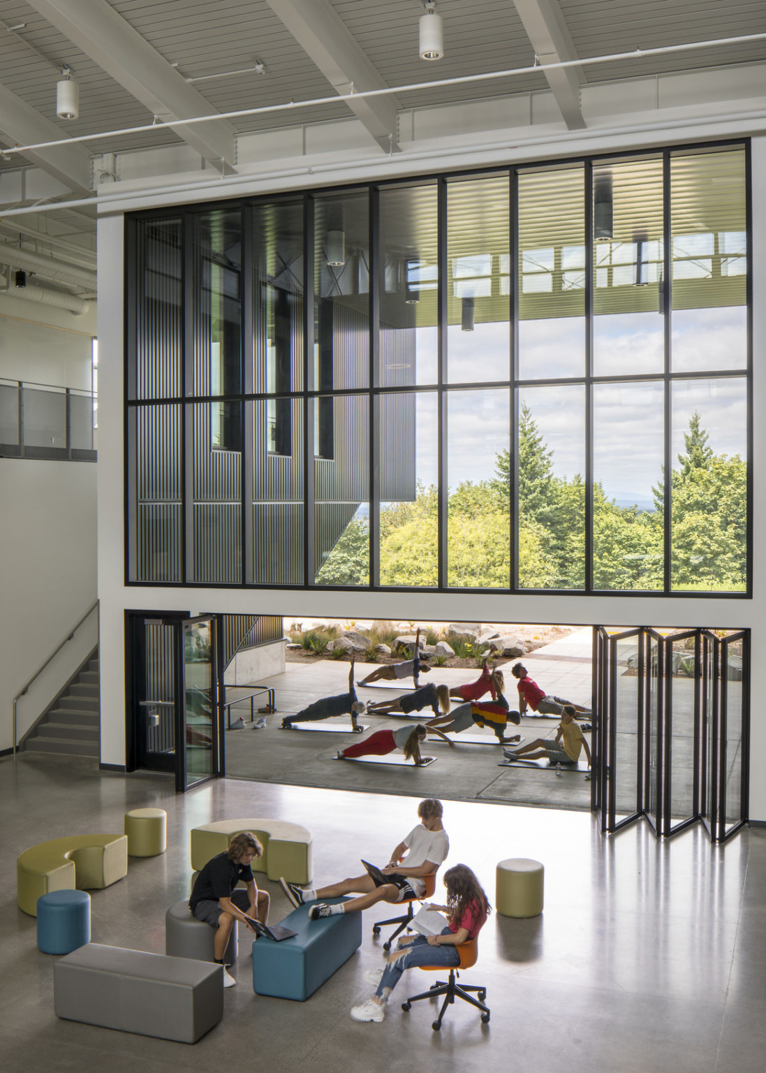 Lower wall of atrium windows folders open to allow greater patio access. A class is doing yoga outside.