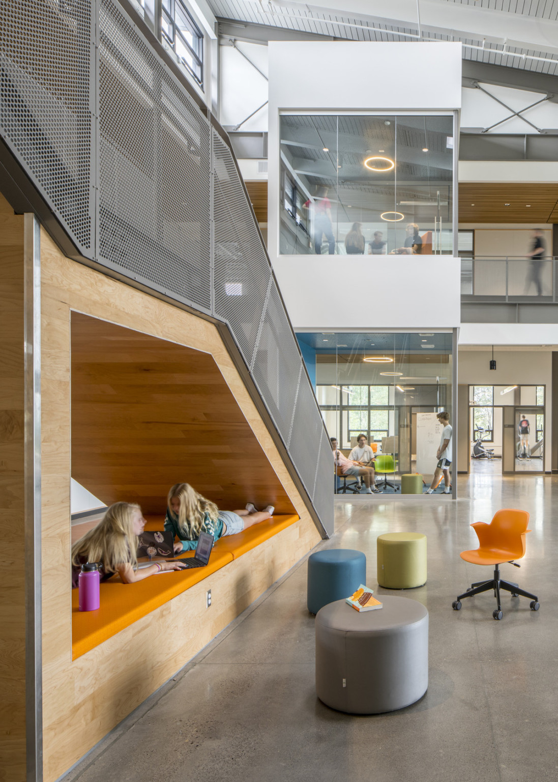 Atrium seen from right of stairs with comfortable padded space under. Ahead, glass learning pods in front of 2nd floor hall