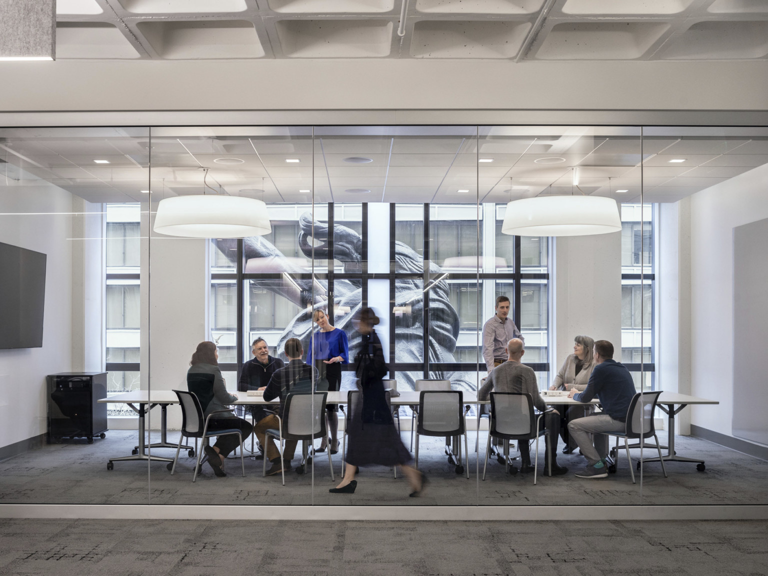 A conference room with glass wall into hallway has floor to ceiling windows looking onto the back of the Portlandia sculpture, portland building renovation, restoration, postmodern architecture, michael graves architecture