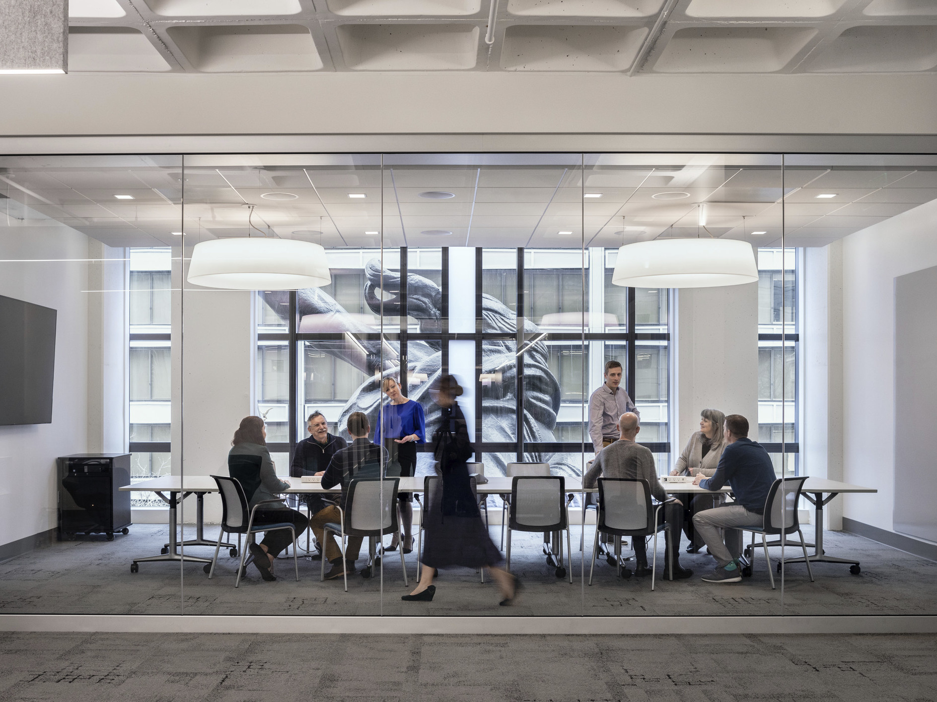 A conference room with glass wall into hallway has floor to ceiling windows looking onto the back of the Portlandia sculpture, portland building renovation, restoration, postmodern architecture, michael graves architecture