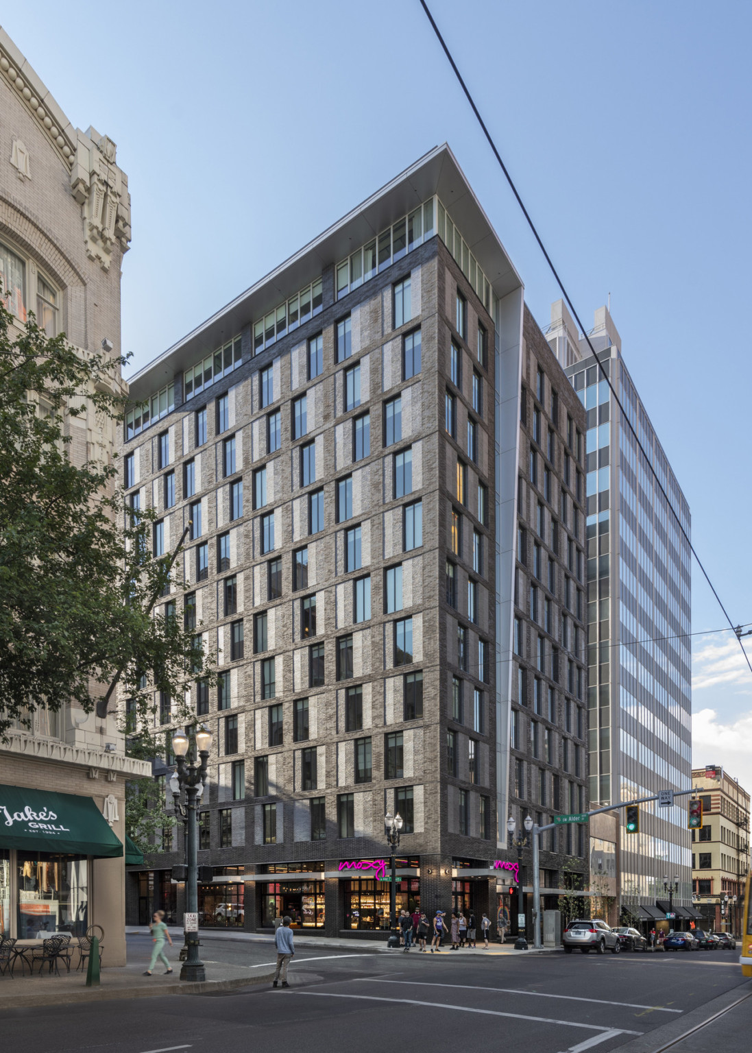 View of hotel from corner across the street. A 12 story building with floor to ceiling windows in lobby and top floor