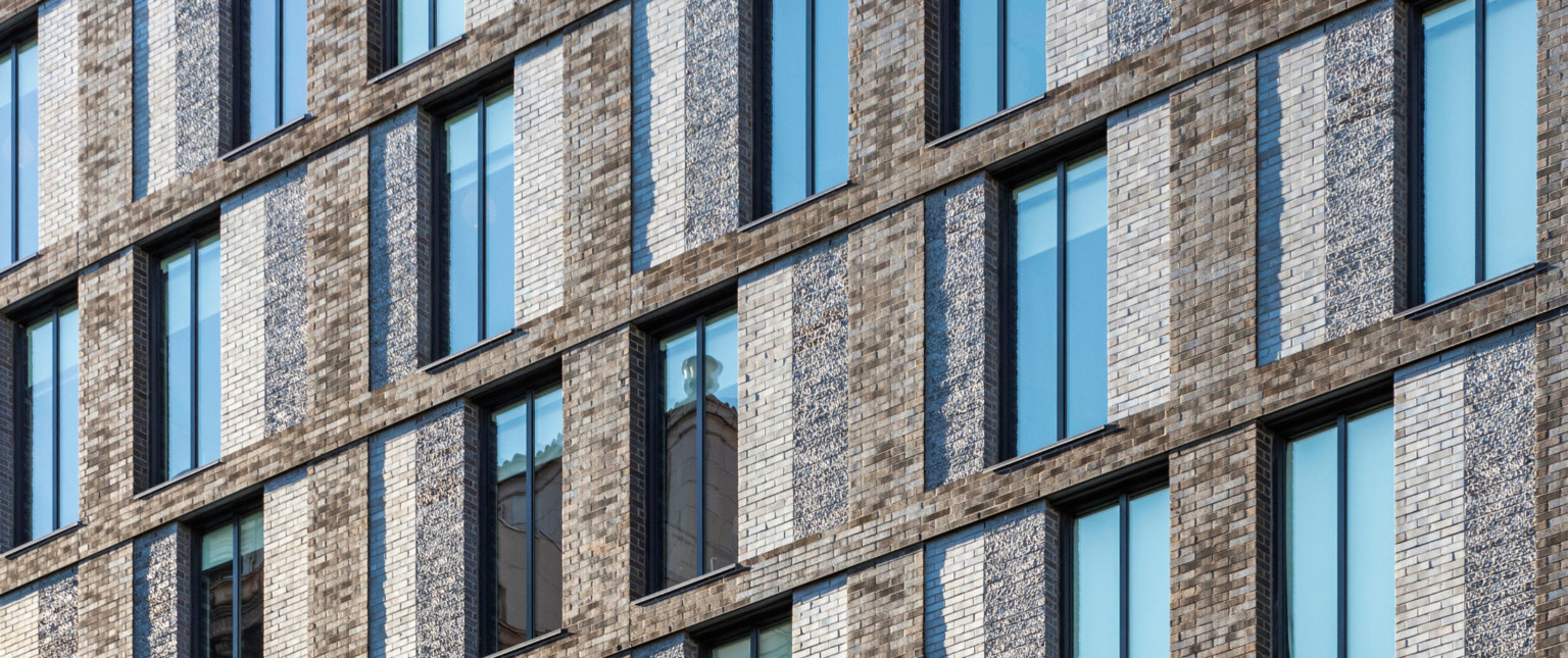 Closeup view of brick and stone wall of building with long thin double windows