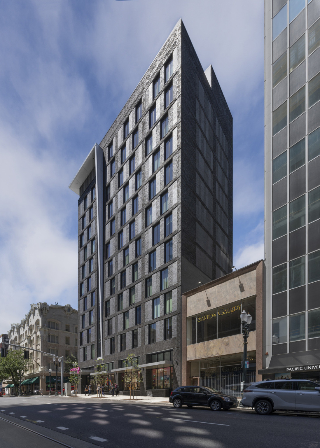 Exterior view from back corner across the street. Grey flat awnings shade side windows at ground level