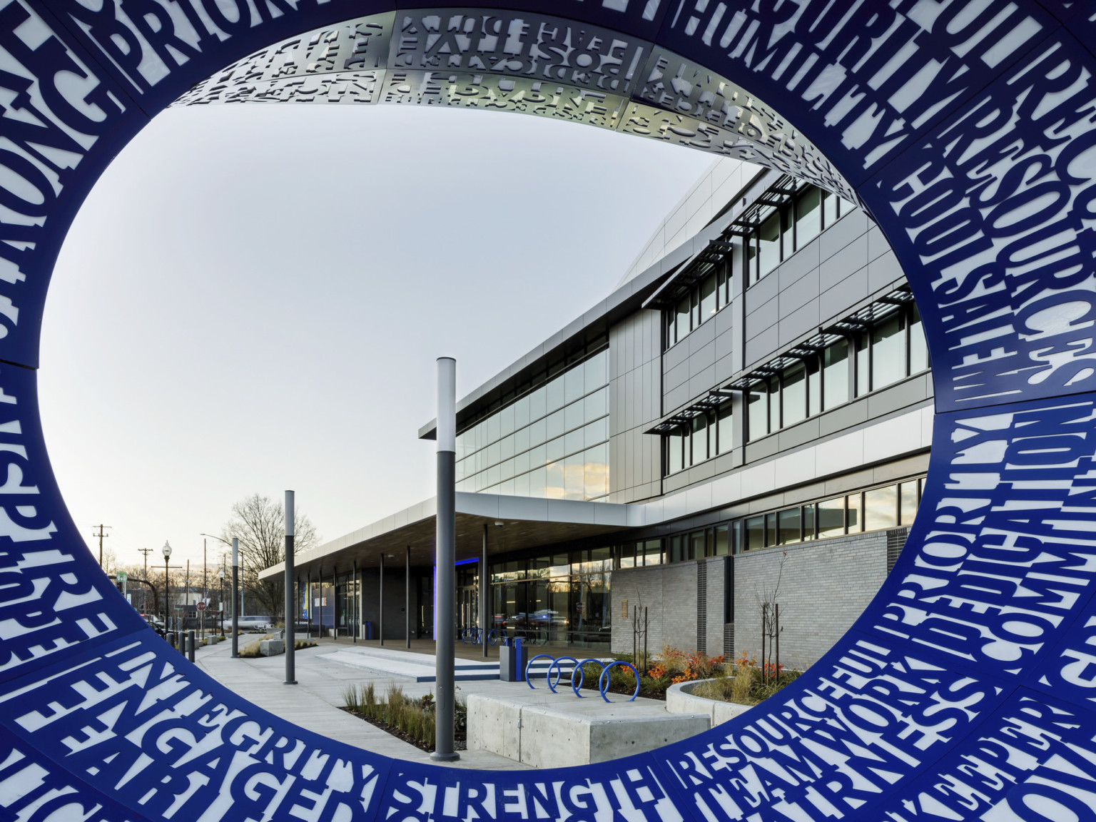 Close up of the sculpture showing different values written in blue around circle through which building entrance can be seen