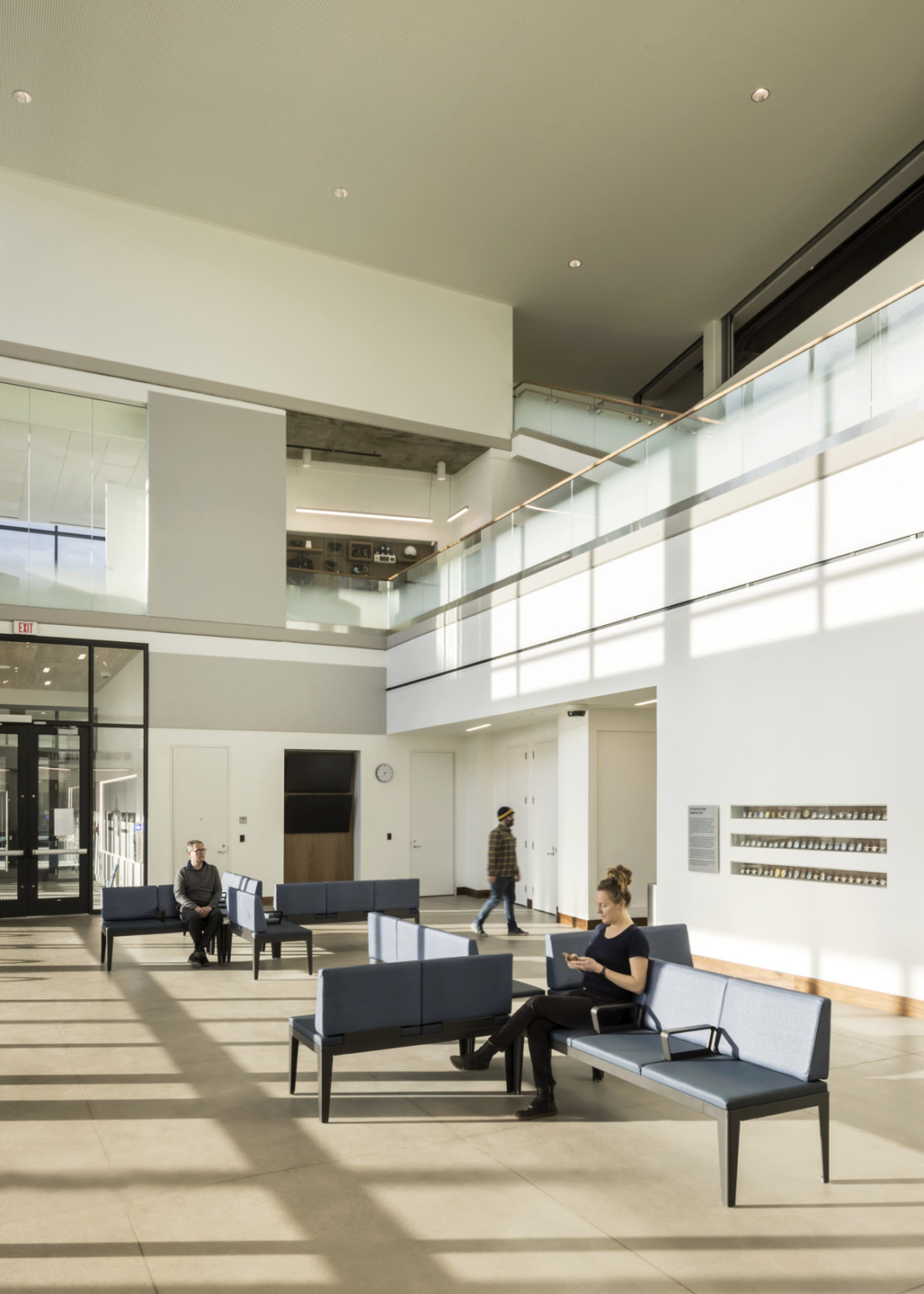 Natural light heavy entry room with multiple seating areas below cutout floorplan to 2 more stories with translucent bannisters