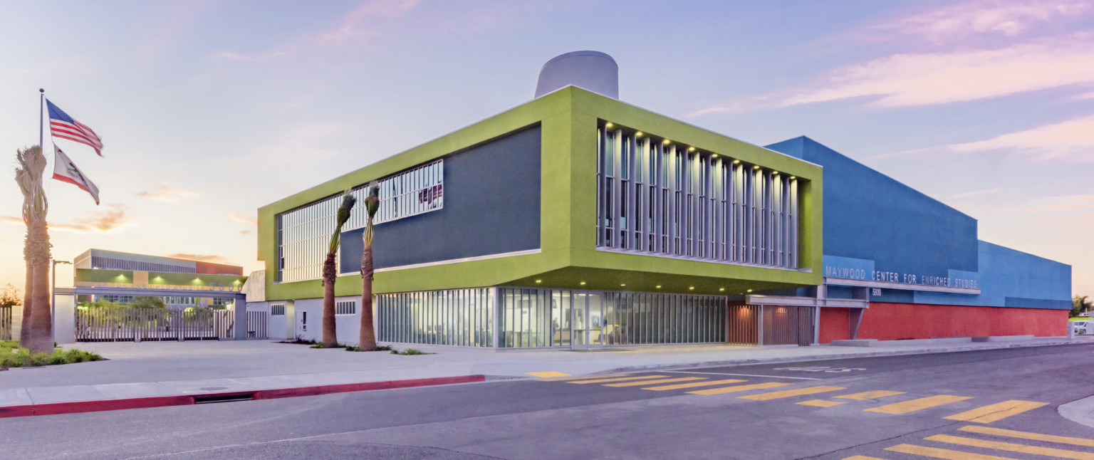 Back corner of library. Floor to ceiling windows on first floor recessed below double height green stucco wrapped facade