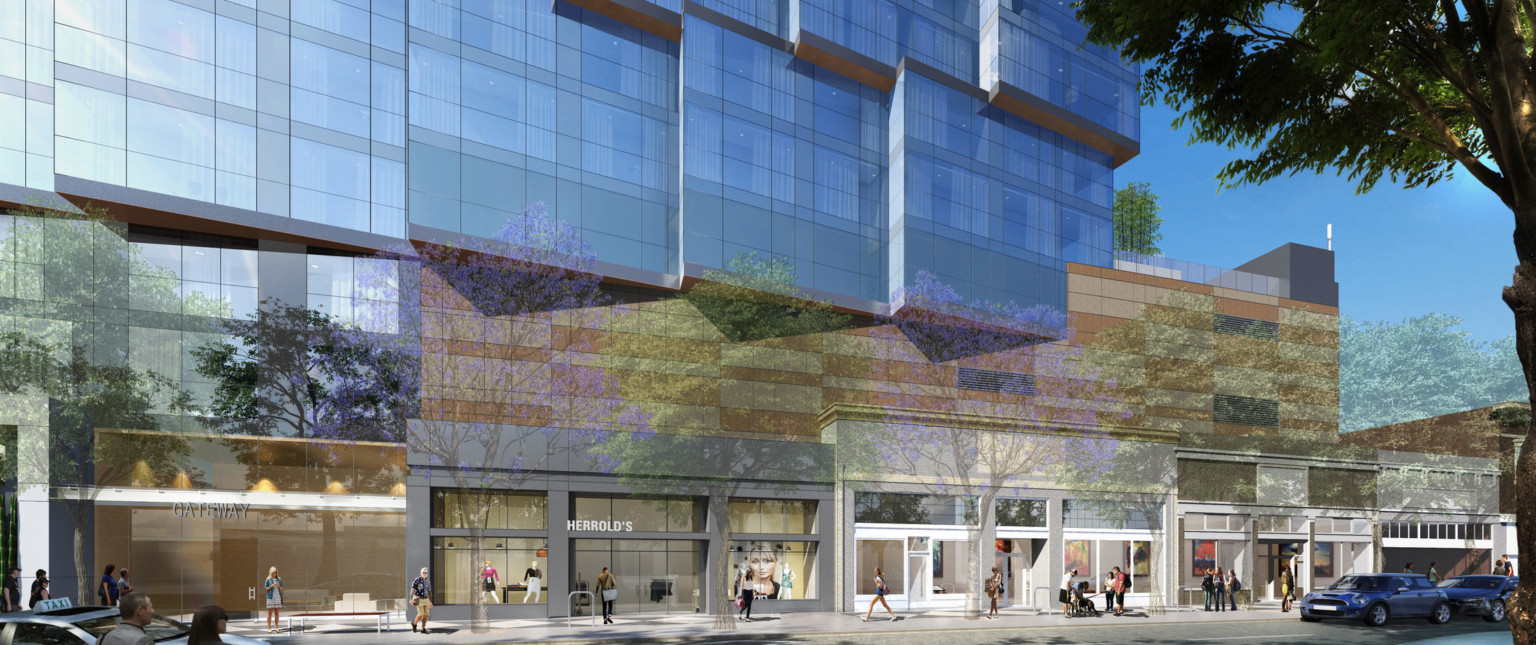 Street level store fronts in building. Above, panel portion of wall below angled stepped glass. Balcony on 4th floor, right