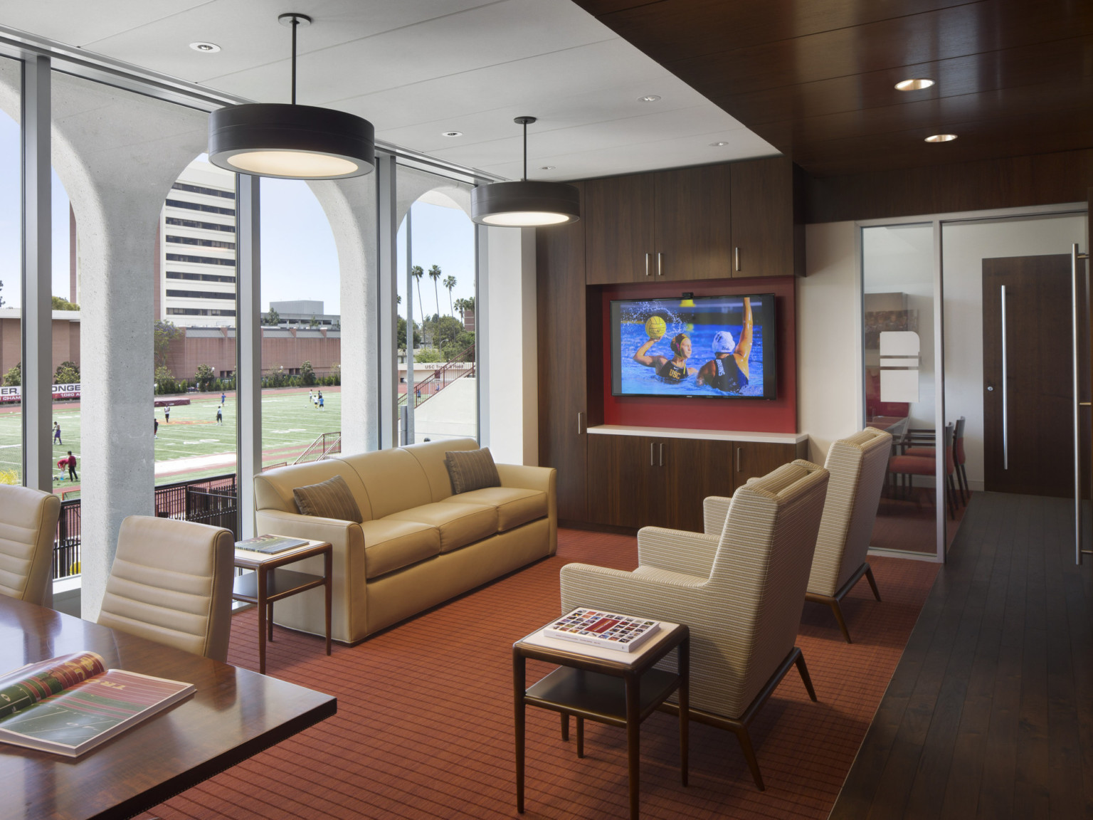 Seating area with television in wood panel room with white accents. Floor to ceiling windows with archway facade, left