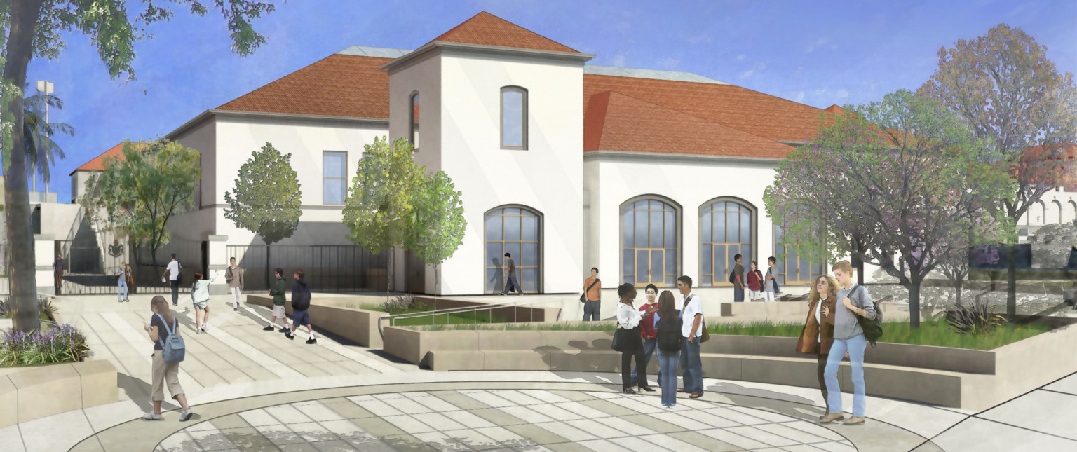 Rounded intersection with stone bench seating in courtyard. Behind, a white Spanish style 2 story building with red roof