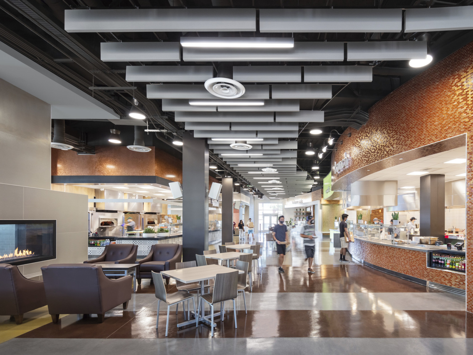 Interior hallway with ride tile detailing around food stations. Flexible seating area, front, next to beige fire place